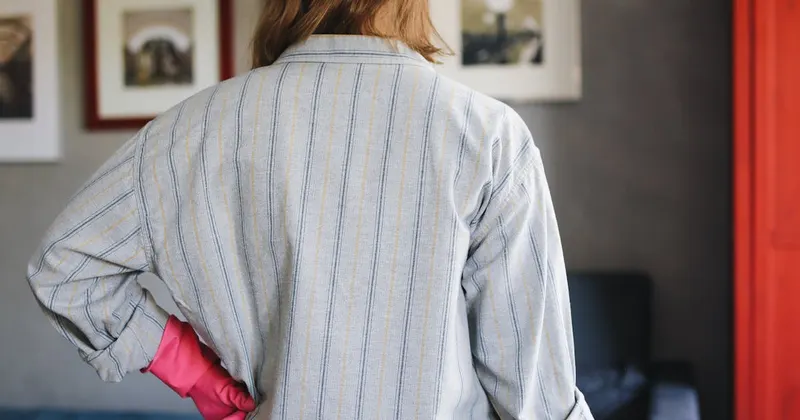 Person wearing rubber gloves handling laundry cleaning supplies