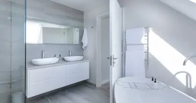 Crop faceless person in yellow latex protective glove cleaning surface of white stylish sink in