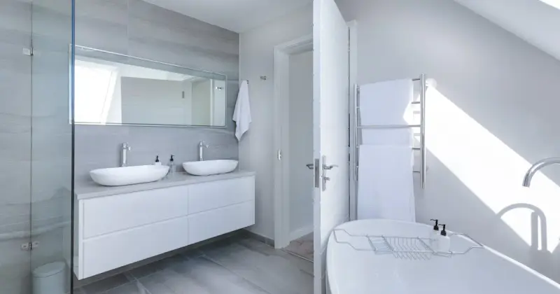 Crop faceless person in yellow latex protective glove cleaning surface of white stylish sink in