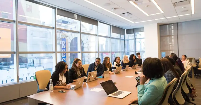 Diverse team collaborating in a modern office setting with laptops and documents.