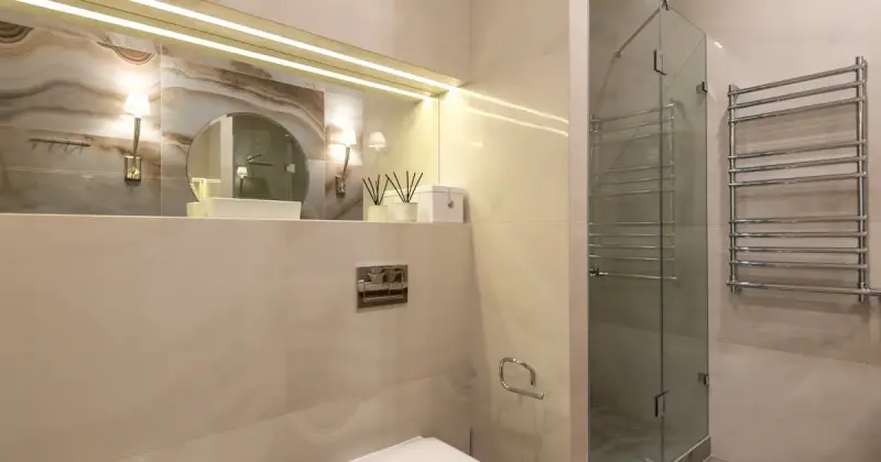 Luxurious modern bathroom with marble tiled shower and sleek glass doors.