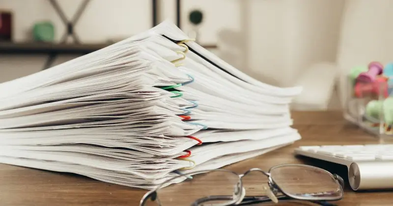 Close-up of paper-clipped documents stacked on a desk