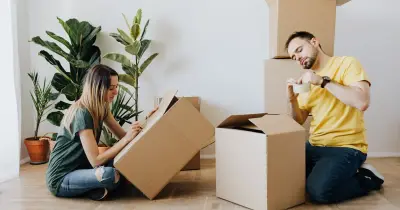 Tired woman leaning on a moving box while packing and relocating to a new home.