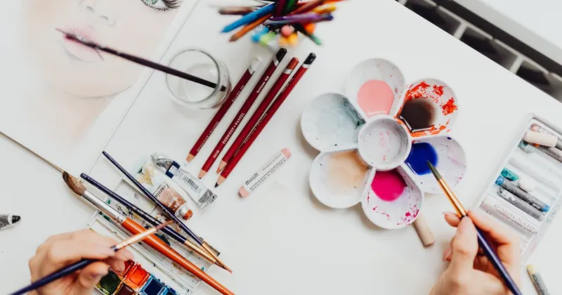 Art materials including paintbrushes and watercolor paints on workspace