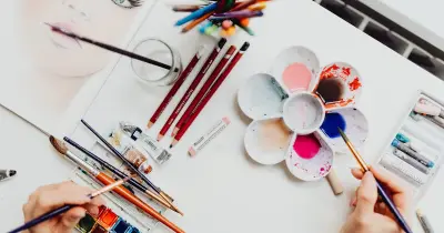 Art materials including paintbrushes and watercolor paints on workspace