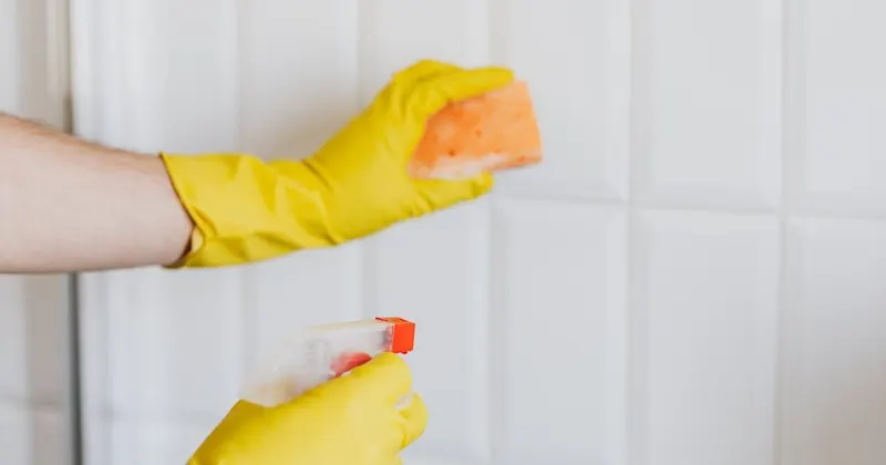 Person in rubber gloves cleaning tiles with a sponge