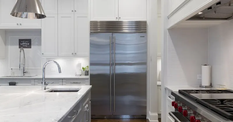 Stainless steel refrigerator beside white kitchen cabinet