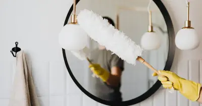 Person cleaning bathroom tile and grout with spray bottle and brush