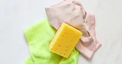 A yellow cleaning sponge over a cleaning cloth