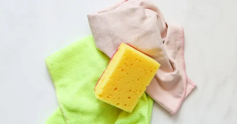 A yellow cleaning sponge over a cleaning cloth