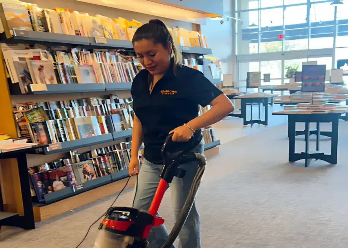 Two SparkTex Cleaners team members in branded polos cleaning a modern office conference room